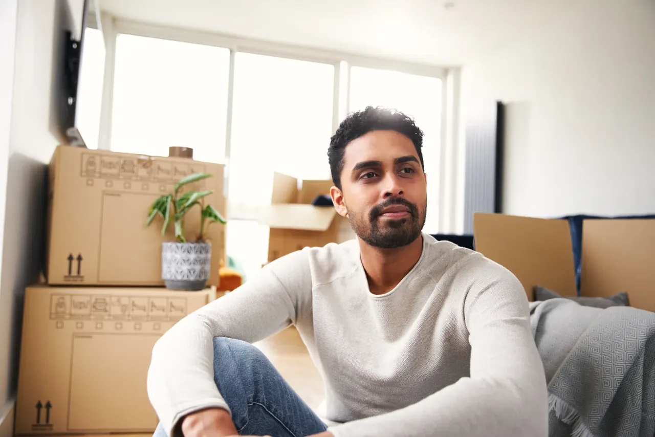 Mann mit Umzugskartons in der neuen Wohnung