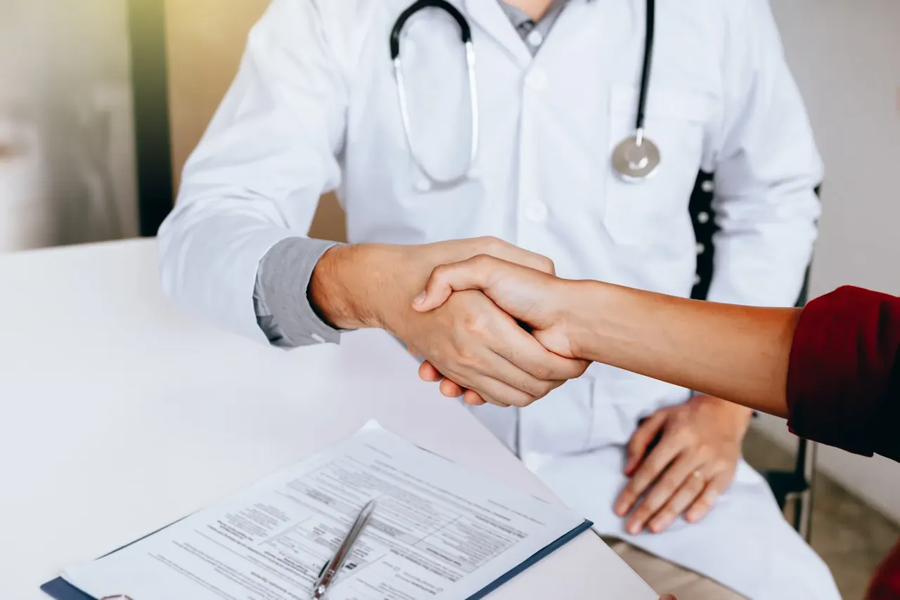 Arzt gibt einer Patientin die Hand in der Praxis
