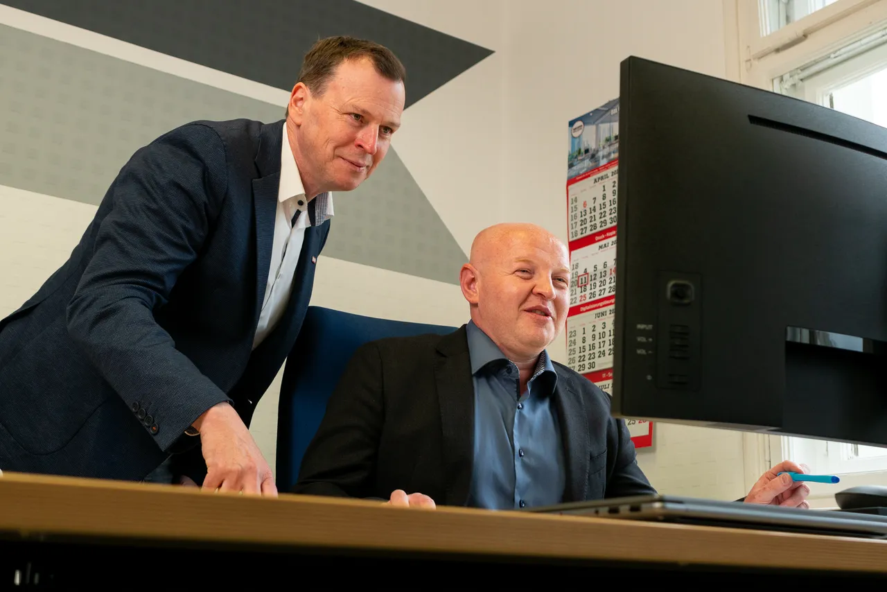 Jens Stölzel bespricht mit einem Kollegen Unterlagen am Bildschirm im Büro in Leipzig